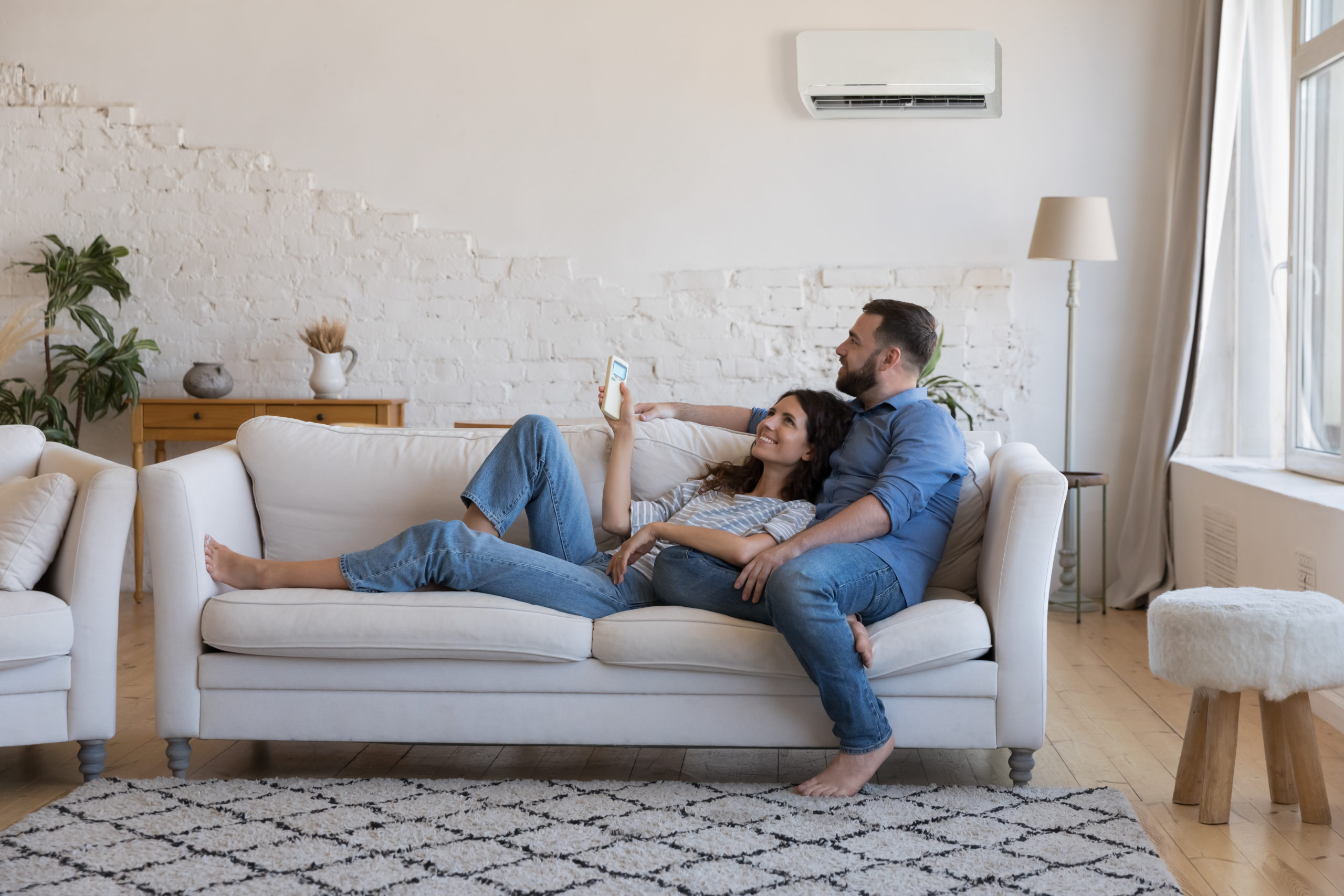 happy couple laying on couch with comforting HVAC improving air circulaiton